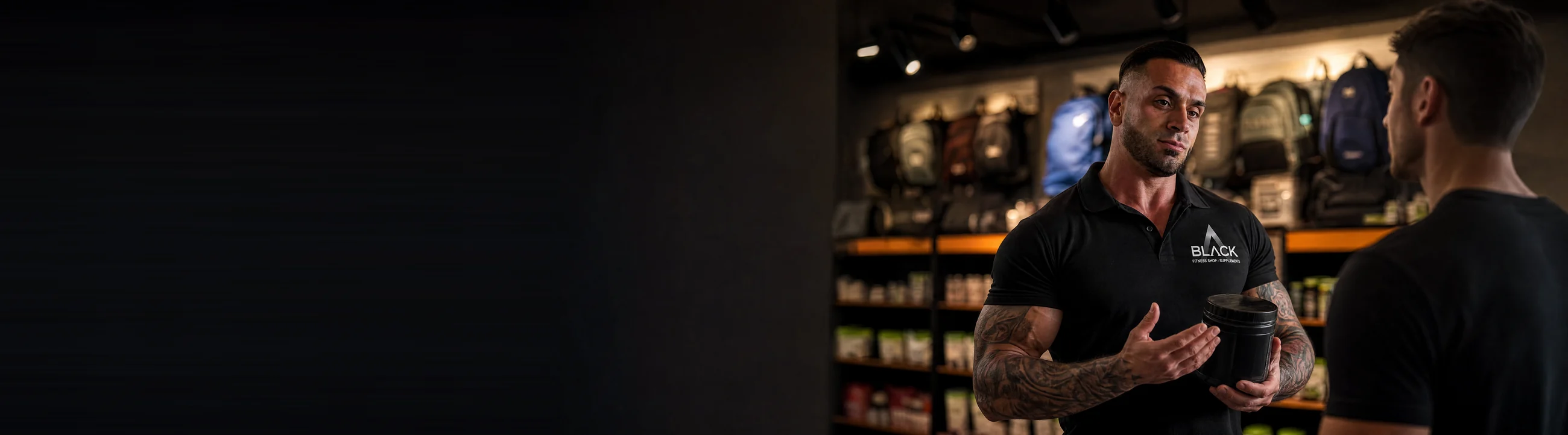 Leonardo, con la chomba de Black Fitness Shop, explicándole un suplemento a un cliente dentro del local